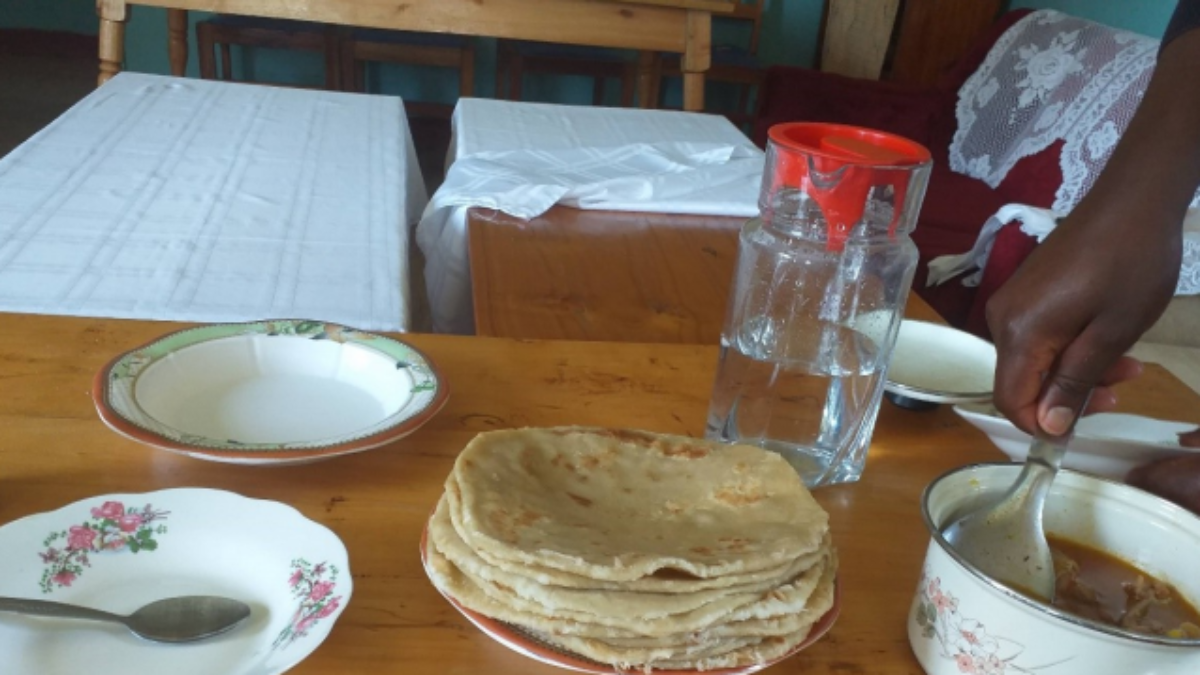 Ein Tisch gedeckt mit Tellern, Teigfladen und einem Topf gefüllt mit Soße